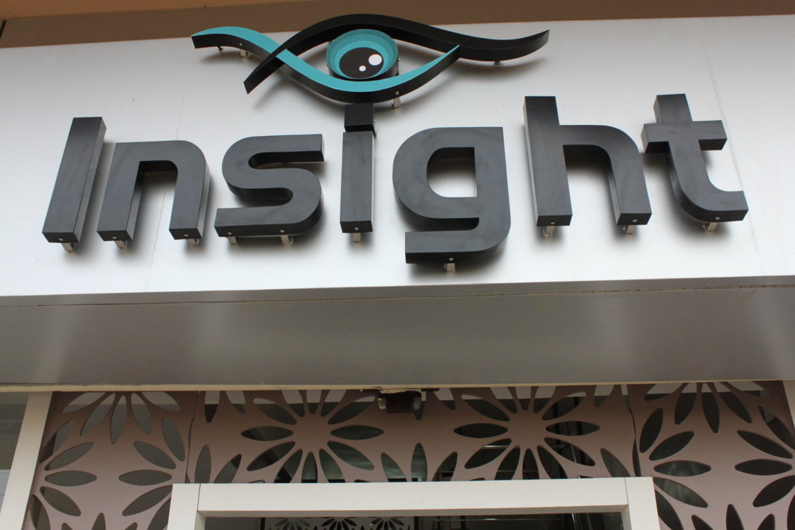 Insight Institute illuminated brand marquee mounted above the entrance, with floral cutout privacy panels framing the doorway below